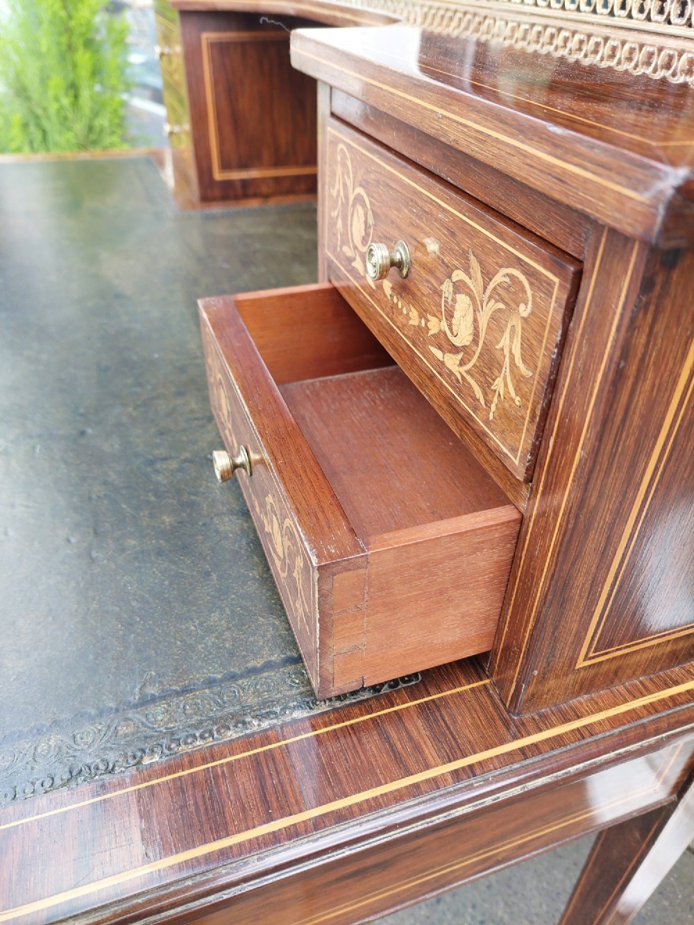 Late Victorian inlaid mahogany writing desk featuring an upper mirror-backed superstructure with brass gallery, leather writing surface, floral marquetry, and tapered legs on castors. View V
