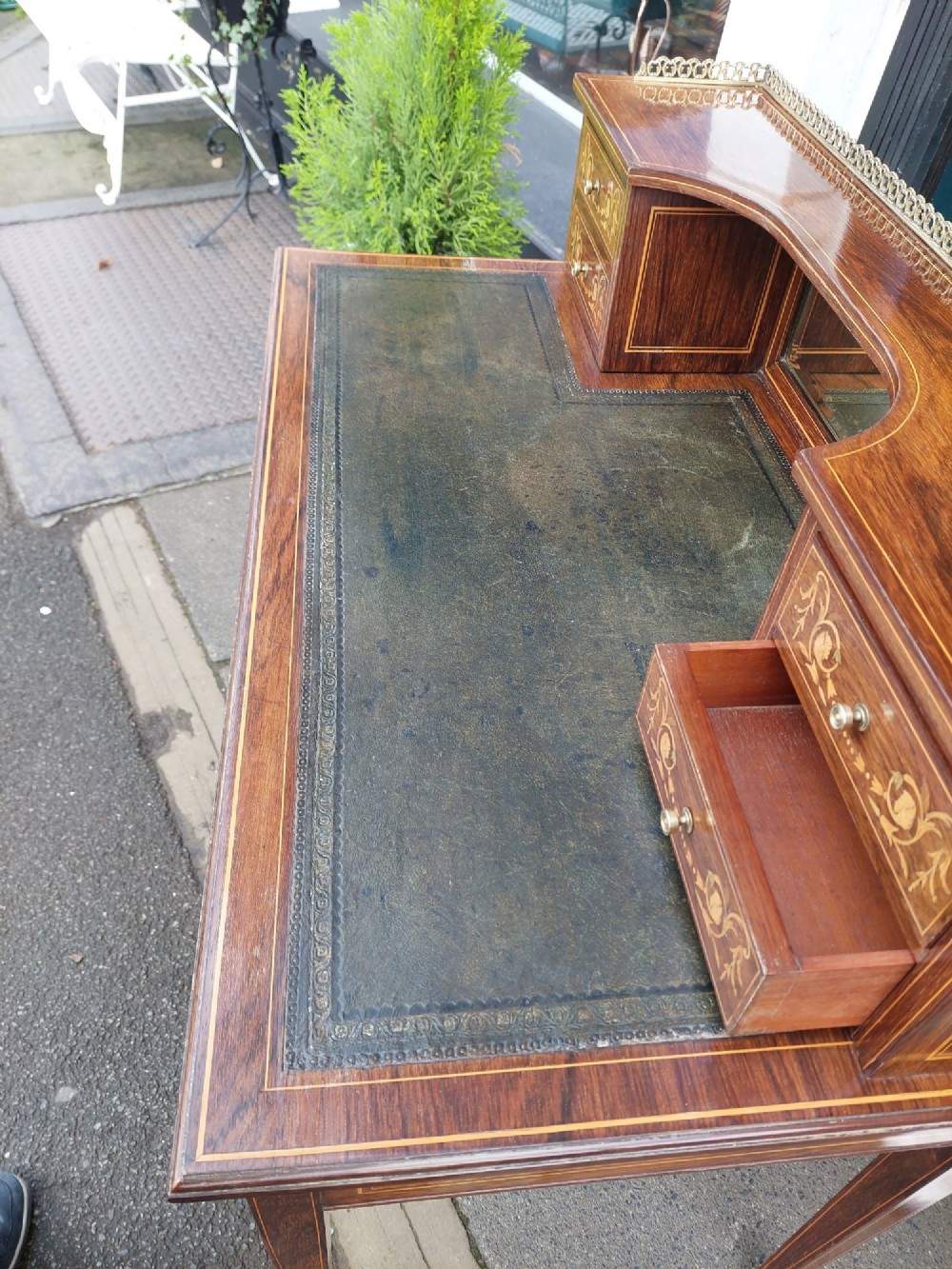 Late Victorian inlaid mahogany writing desk featuring an upper mirror-backed superstructure with brass gallery, leather writing surface, floral marquetry, and tapered legs on castors. View VI