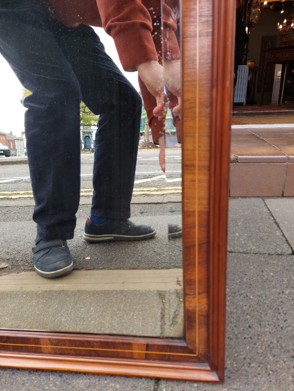 An Edwardian rosewood rectangular overmantel mirror featuring decorative marquetry inlays in the upper corners, a central carved cresting, and a bevelled glass plate. View IV