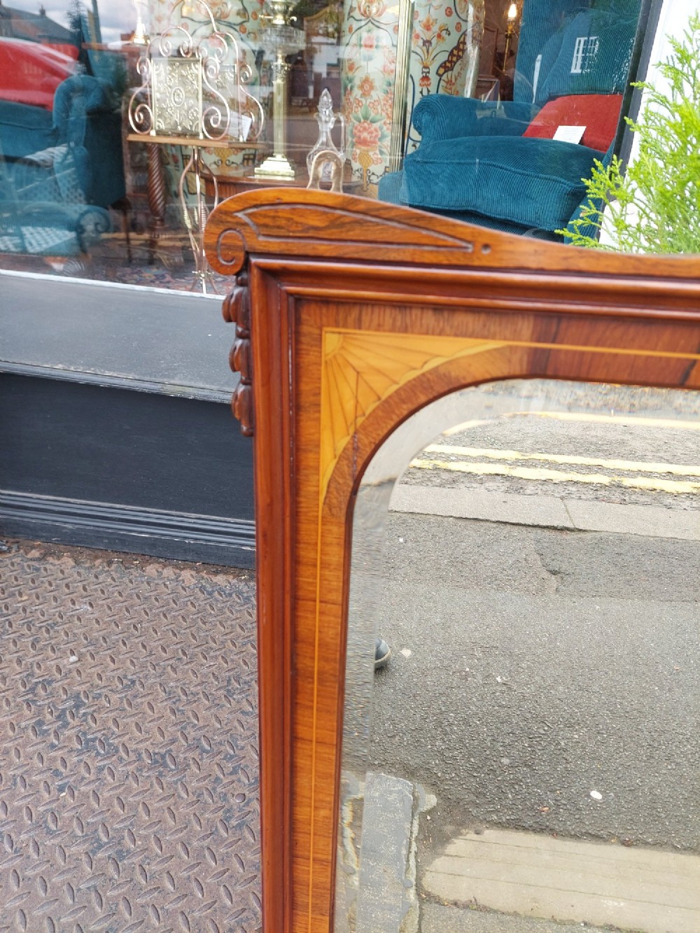 An Edwardian rosewood rectangular overmantel mirror featuring decorative marquetry inlays in the upper corners, a central carved cresting, and a bevelled glass plate. View V