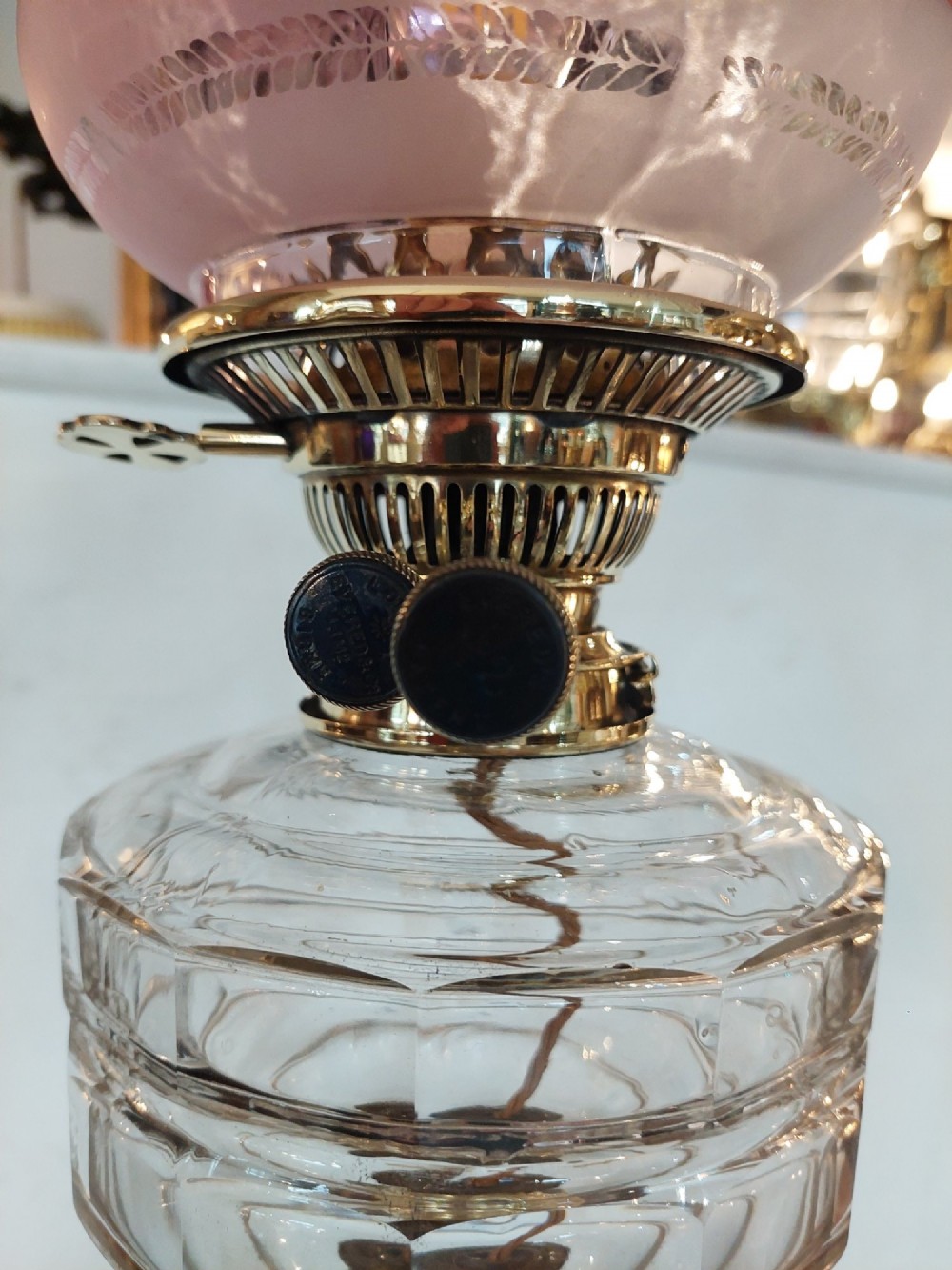 A late 19th-century brass table oil lamp featuring a reeded column, square base, clear glass reservoir, and an etched pink glass shade with a ruffled rim. View V