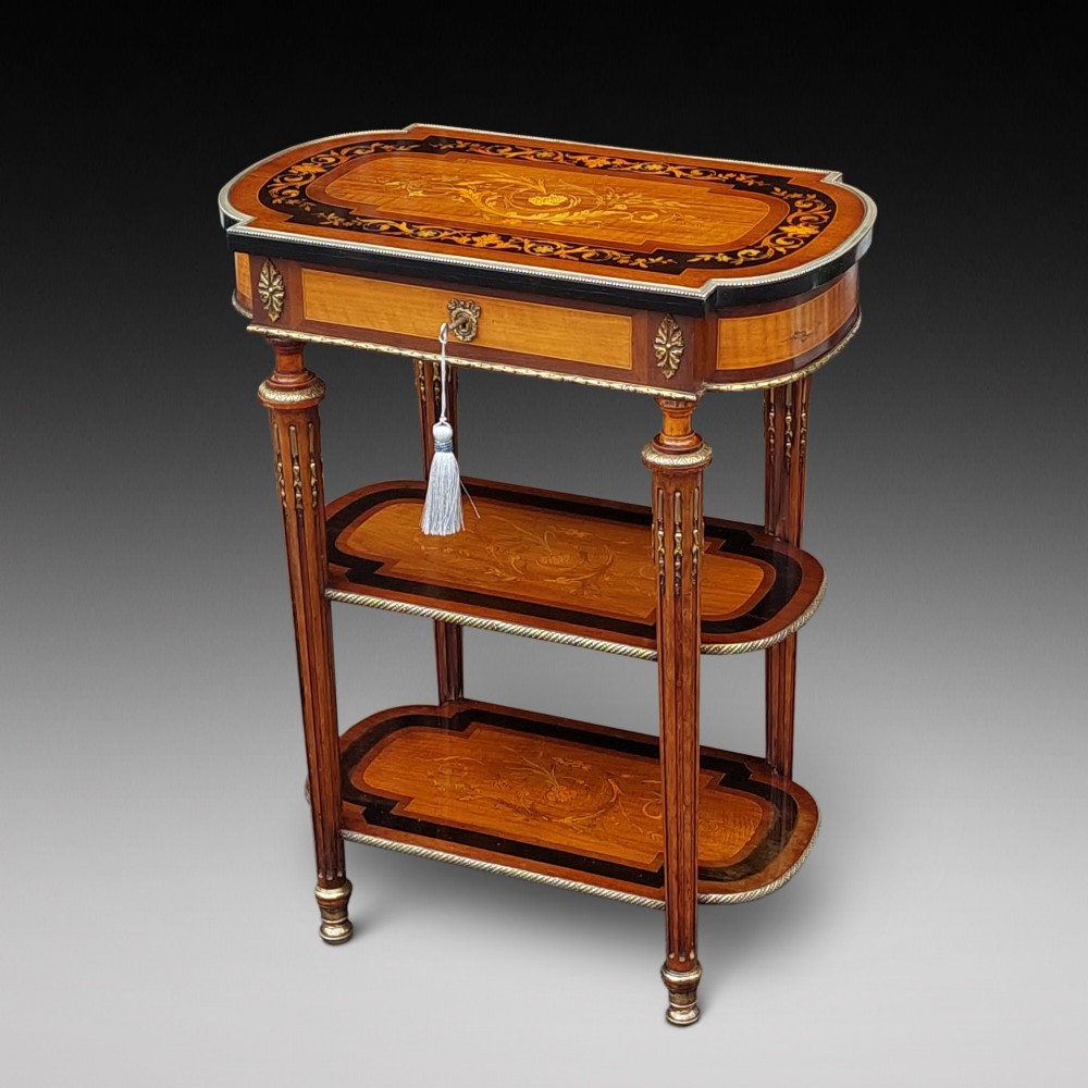 An antique Victorian marquetry whatnot table featuring floral inlay on the top surface, two lower tiers, fluted legs, and gilt-metal mounts.