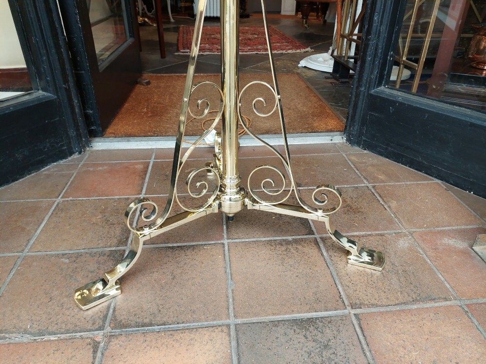 An Edwardian brass standard floor lamp featuring a scrollwork tripod base, an integrated circular tray table, and a fabric shade with fringe and tassels. View II