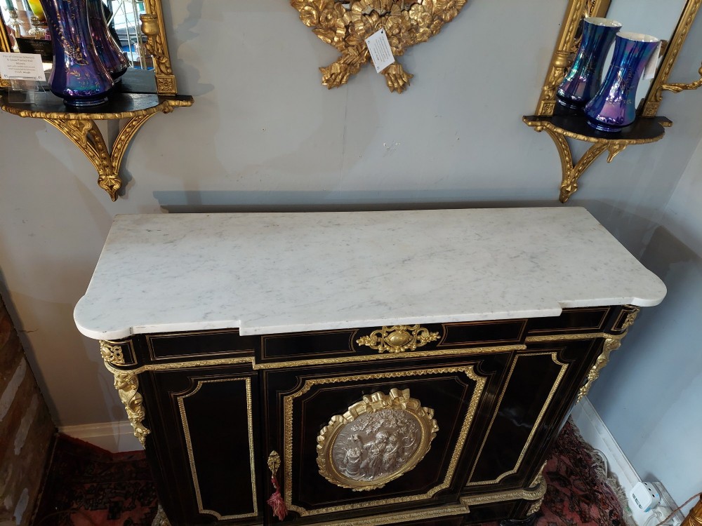 A French Napoleon III ebonised side cabinet featuring a white marble top, gold brass inlays, gilt-bronze ormolu mounts, and a central oval medallion. View II