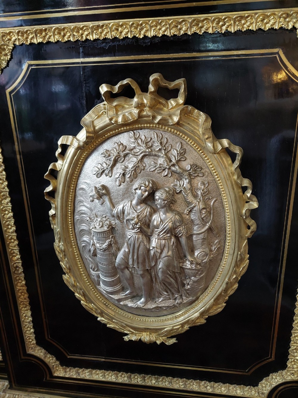 A French Napoleon III ebonised side cabinet featuring a white marble top, gold brass inlays, gilt-bronze ormolu mounts, and a central oval medallion. View III