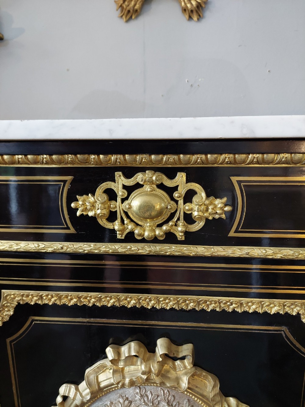 A French Napoleon III ebonised side cabinet featuring a white marble top, gold brass inlays, gilt-bronze ormolu mounts, and a central oval medallion. View IV