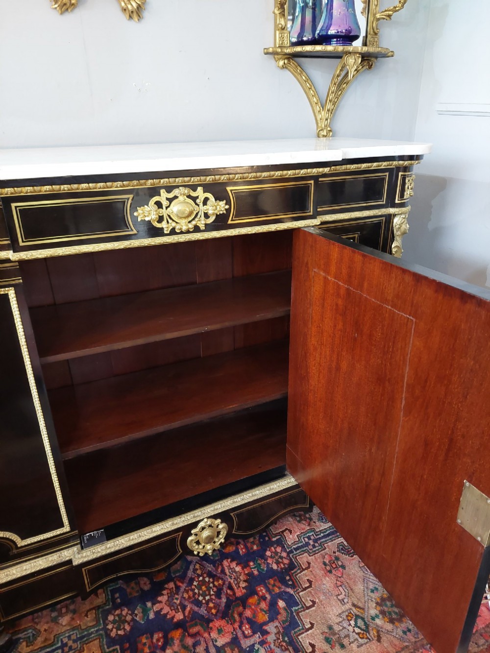 A French Napoleon III ebonised side cabinet featuring a white marble top, gold brass inlays, gilt-bronze ormolu mounts, and a central oval medallion. View XI