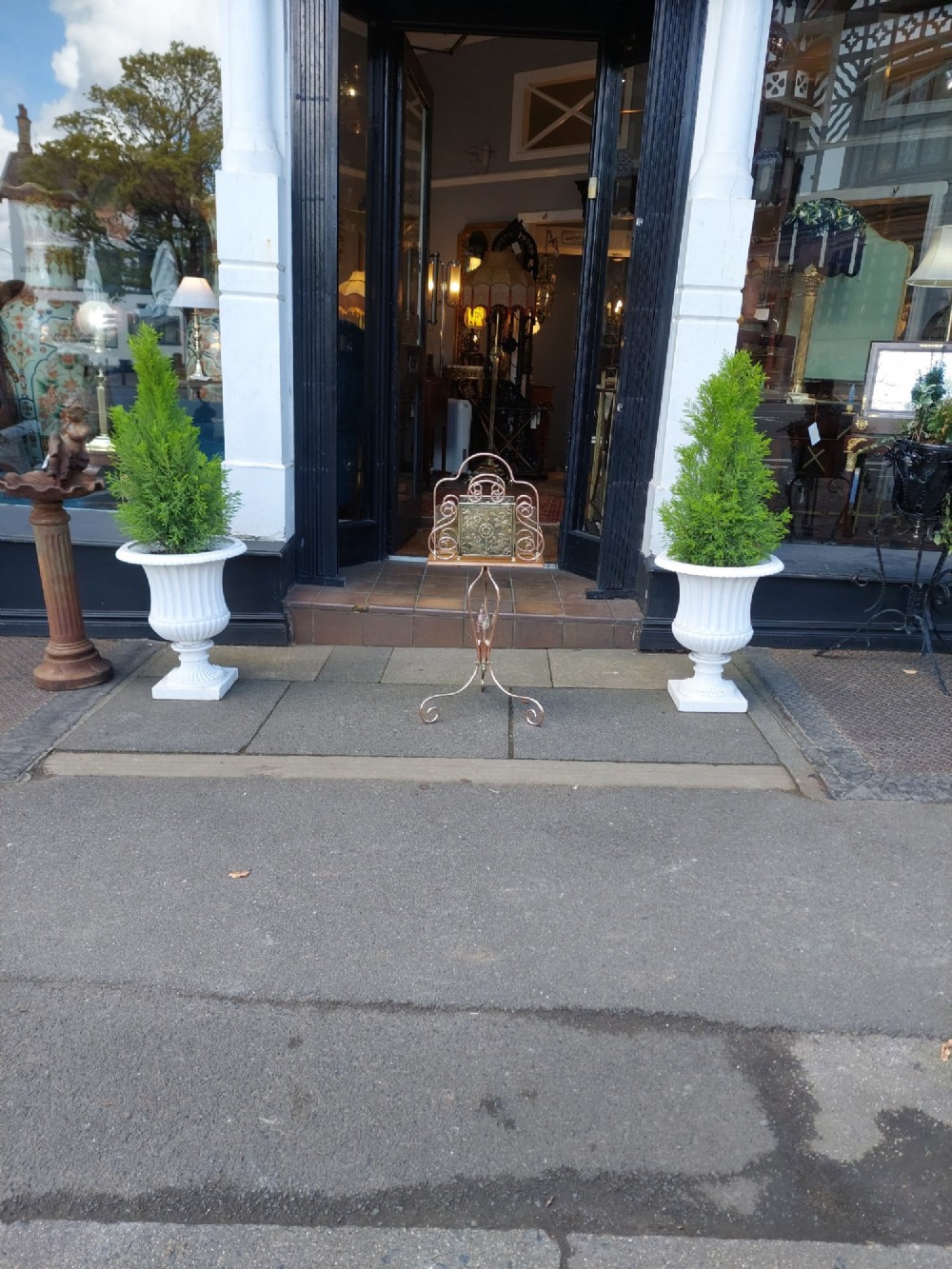 An Arts and Crafts copper and brass standing magazine rack featuring embossed floral metal panels, decorative wire scrollwork, and a tripod base with curved feet. View II
