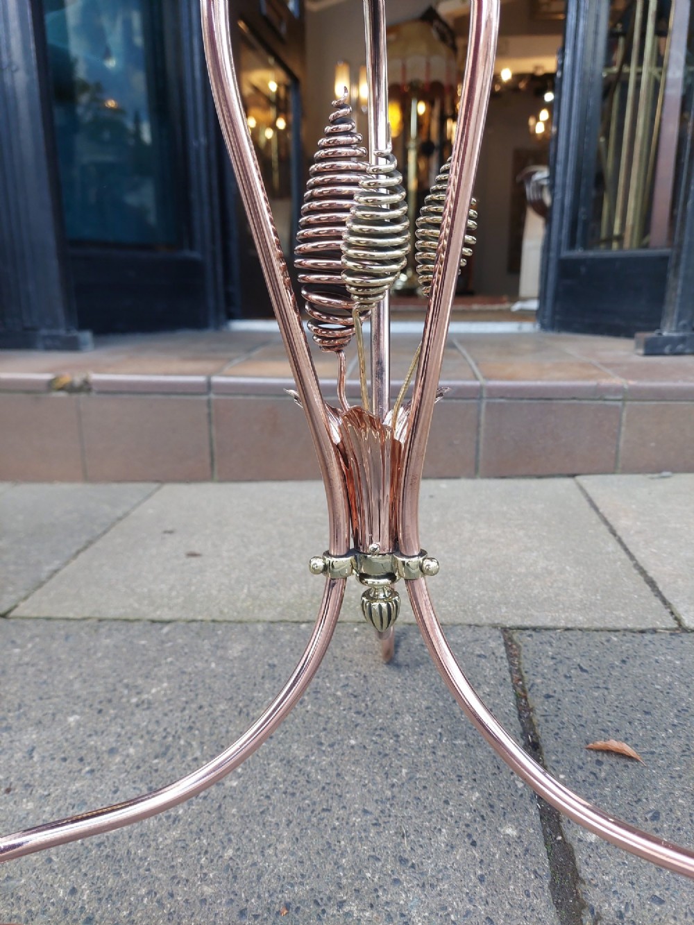 An Arts and Crafts copper and brass standing magazine rack featuring embossed floral metal panels, decorative wire scrollwork, and a tripod base with curved feet. View V