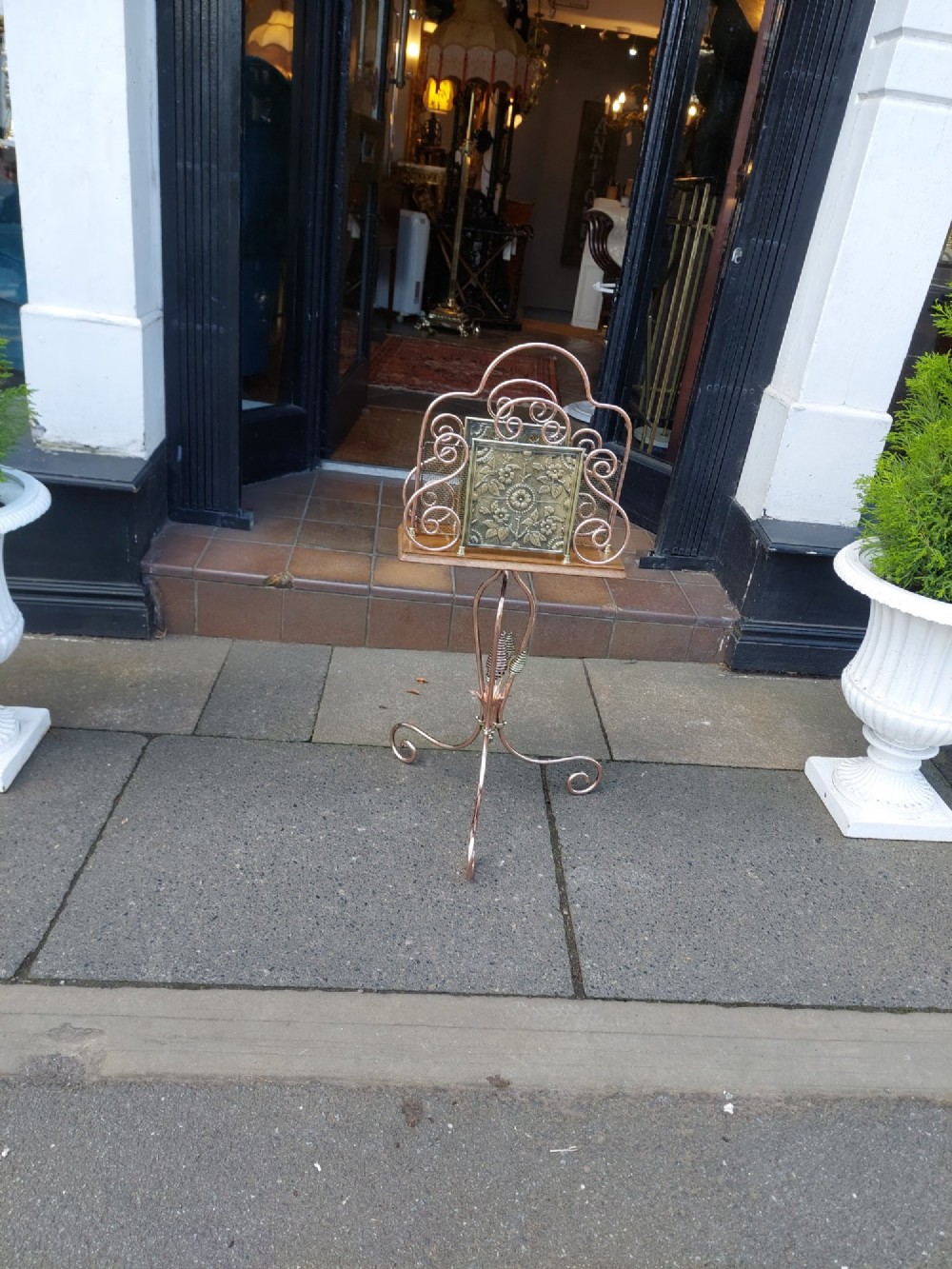 An Arts and Crafts copper and brass standing magazine rack featuring embossed floral metal panels, decorative wire scrollwork, and a tripod base with curved feet. View VIII