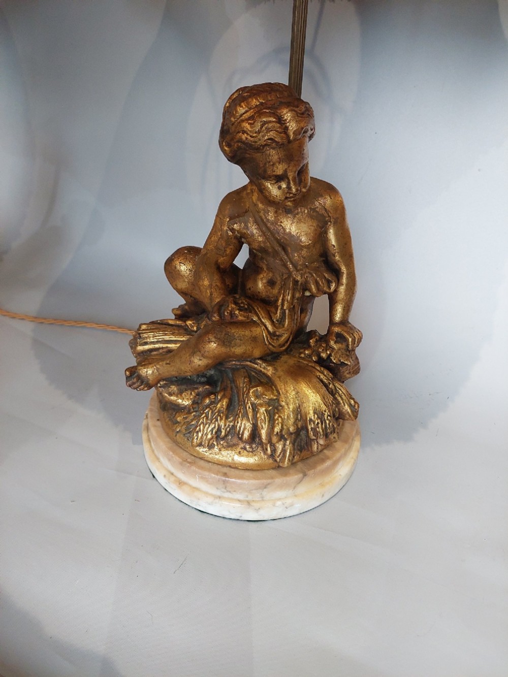 A pair of ornate table lamps featuring gilded cherub figures mounted on white alabaster bases, topped with fringed dome fabric shades. View IV