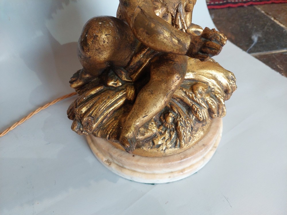 A pair of ornate table lamps featuring gilded cherub figures mounted on white alabaster bases, topped with fringed dome fabric shades. View VI
