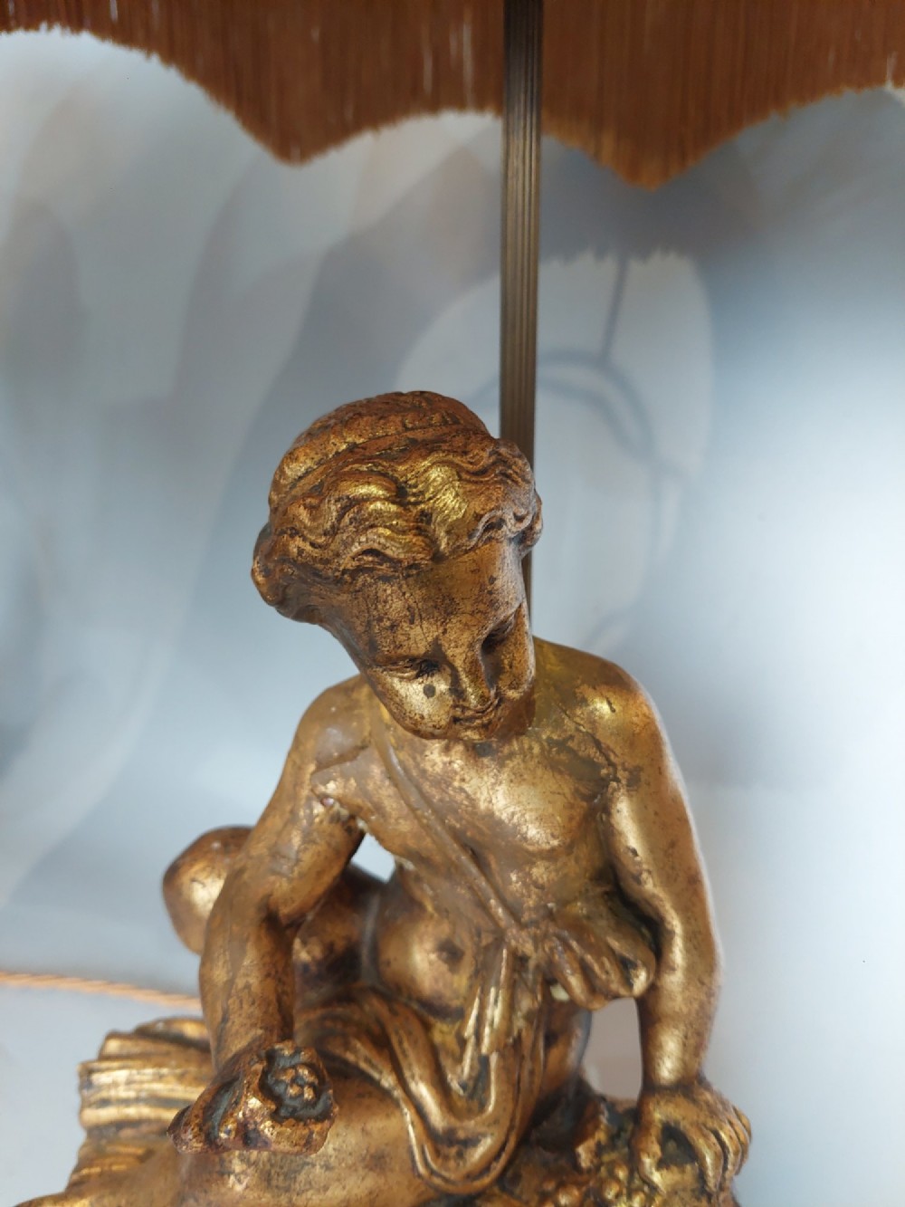 A pair of ornate table lamps featuring gilded cherub figures mounted on white alabaster bases, topped with fringed dome fabric shades. View VII