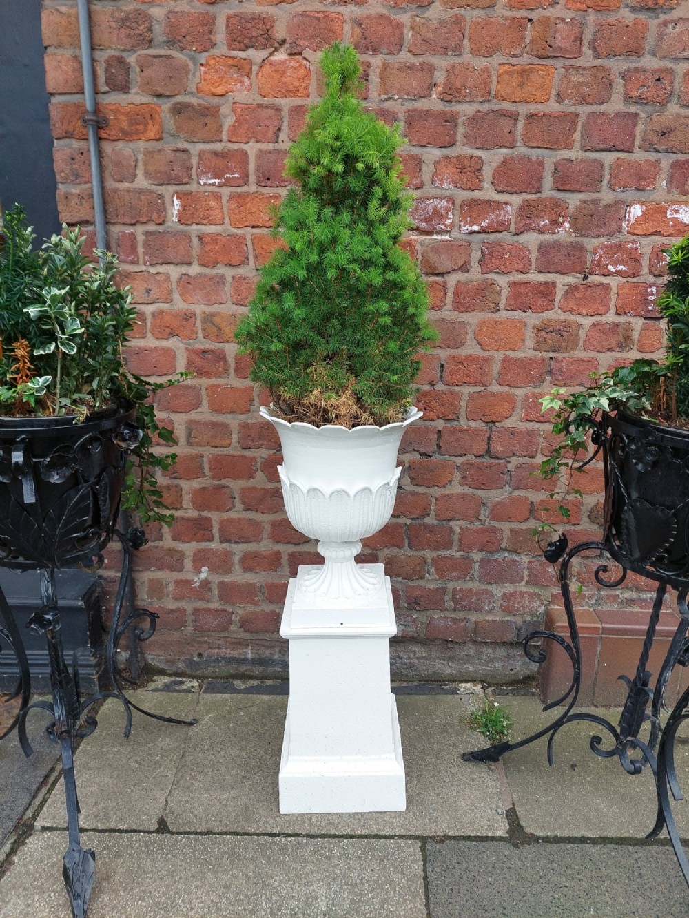 A classical white painted garden urn featuring an acanthus leaf pattern and scalloped rim, positioned on a matching square pedestal stand. View II