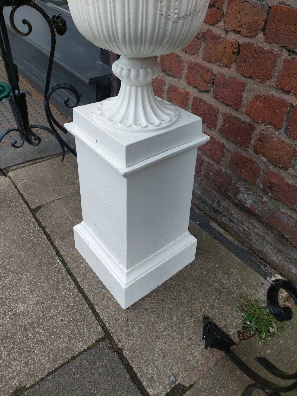 A classical white painted garden urn featuring an acanthus leaf pattern and scalloped rim, positioned on a matching square pedestal stand. View VI