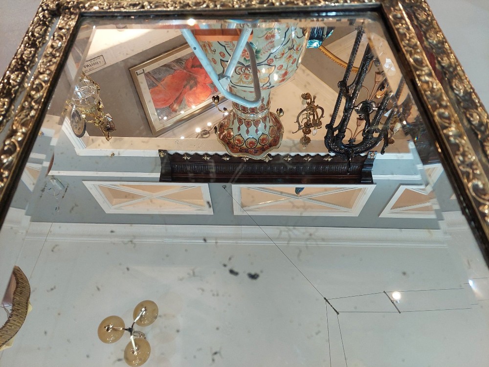 An antique 19th-century French rectangular wall mirror featuring an embossed pressed brass frame with a decorated triangular crest and mirrored border surround. View IV