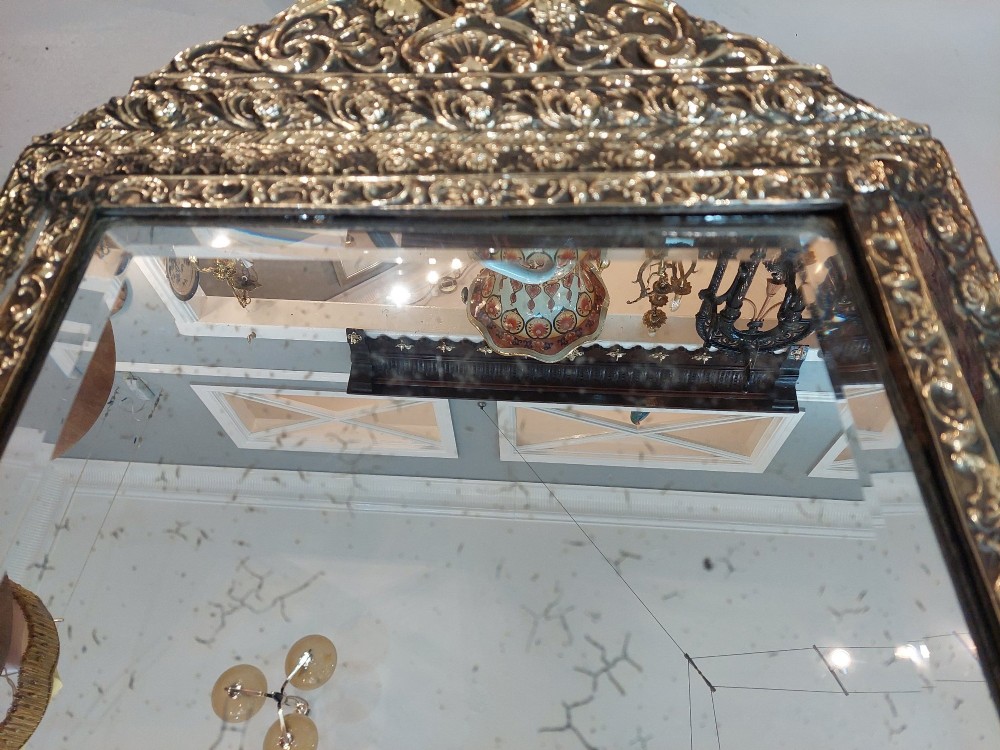 An antique 19th-century French rectangular wall mirror featuring an embossed pressed brass frame with a decorated triangular crest and mirrored border surround. View V