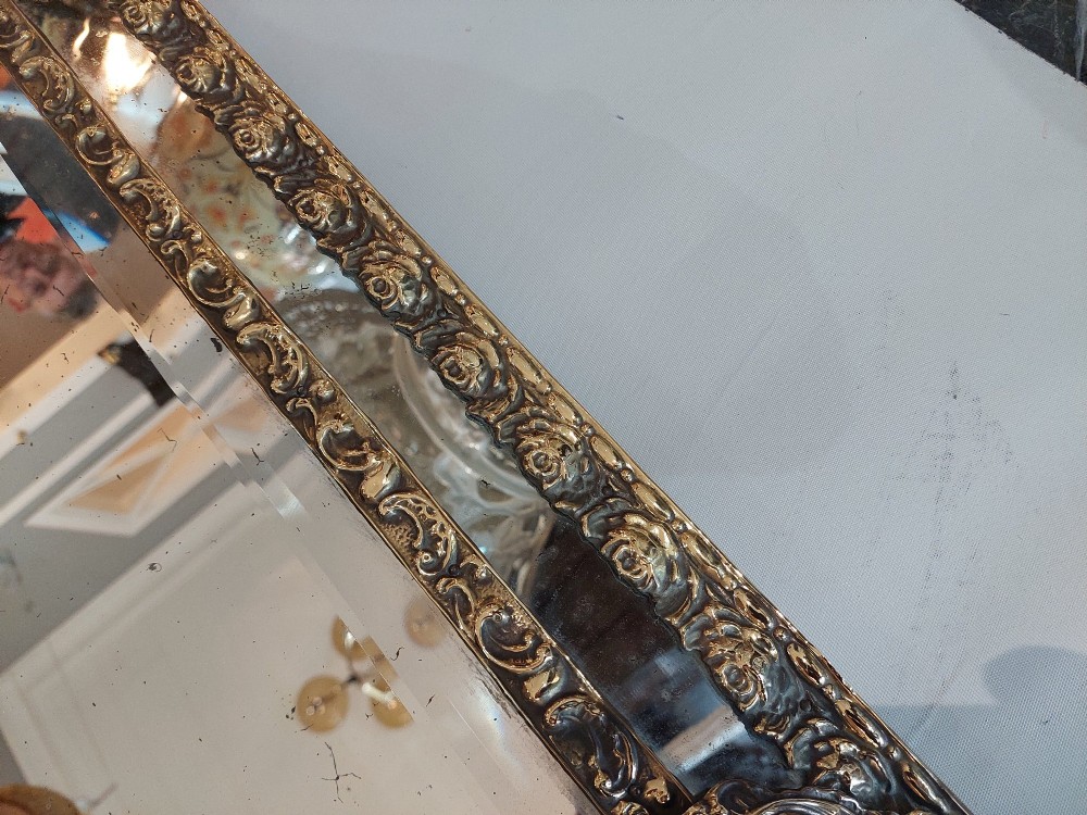 An antique 19th-century French rectangular wall mirror featuring an embossed pressed brass frame with a decorated triangular crest and mirrored border surround. View VIII