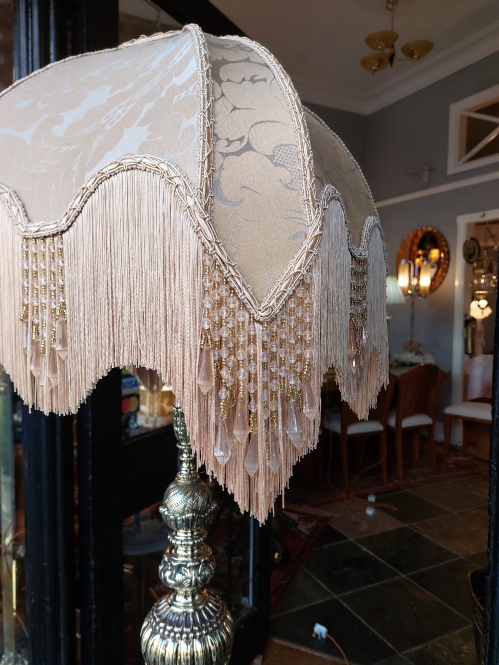 A pair of ornate silvered brass standard lamps featuring detailed turned baluster stems, lobed bases, and cream domed fabric shades with fringed edging. View IV