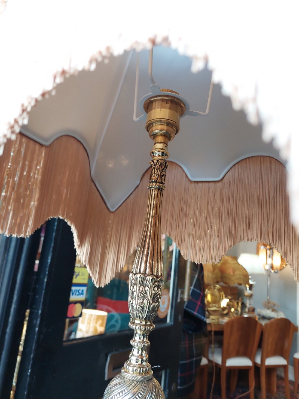 A pair of ornate silvered brass standard lamps featuring detailed turned baluster stems, lobed bases, and cream domed fabric shades with fringed edging. View VI