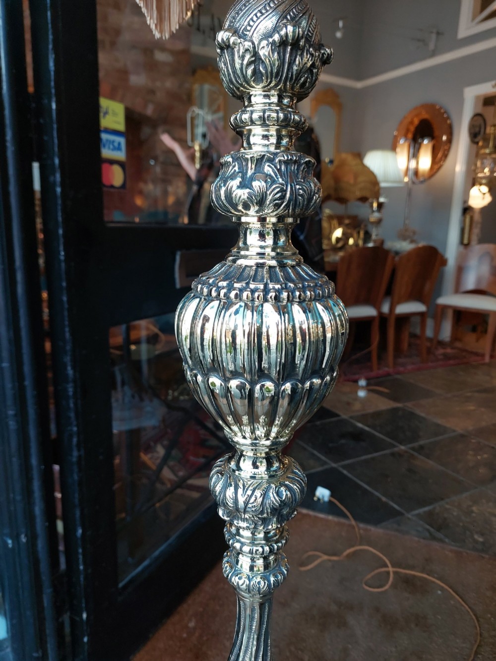 A pair of ornate silvered brass standard lamps featuring detailed turned baluster stems, lobed bases, and cream domed fabric shades with fringed edging. View VII