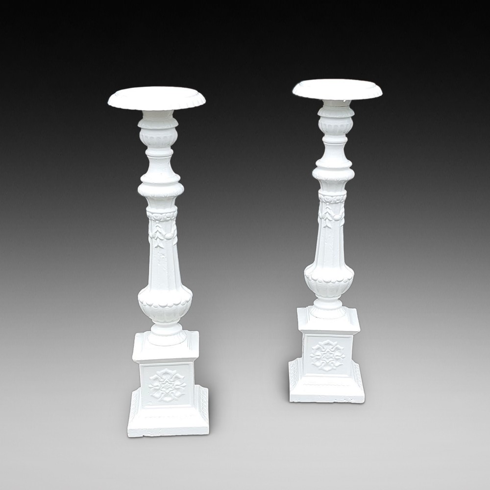 A pair of late 19th-century white painted cast iron garden pedestals with turned column shafts and floral relief square bases.