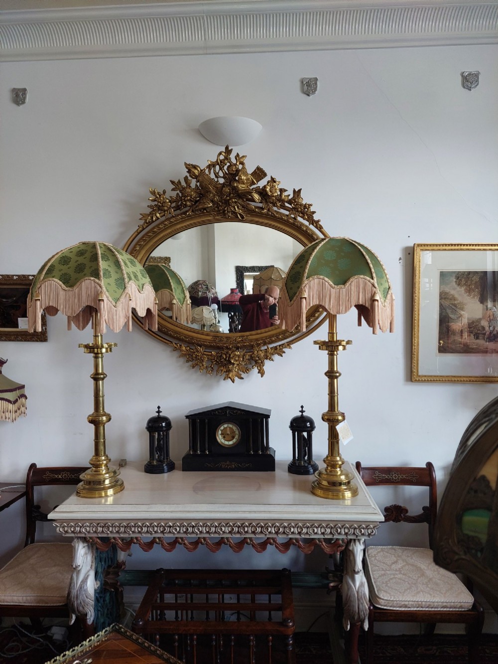 An oval 19th-century carved giltwood wall mirror featuring an intricate top crest with a torch and floral motif and an egg-and-dart inner frame border. View VII