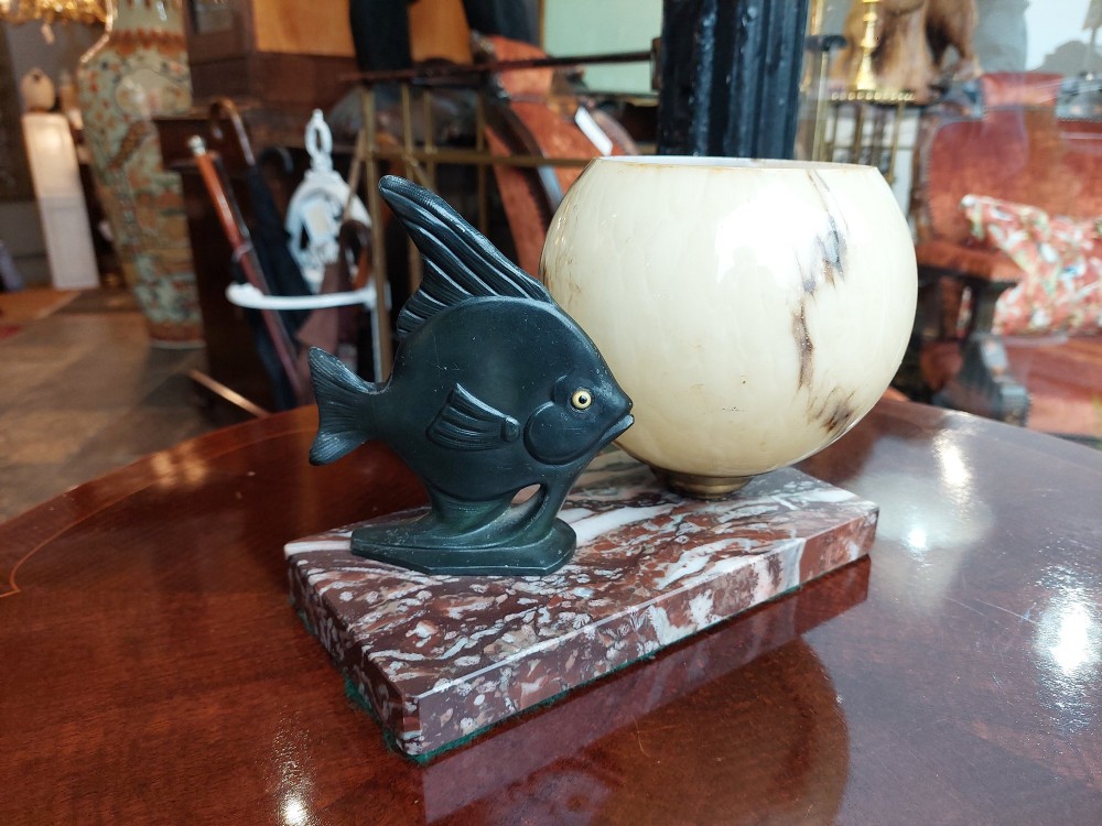 An Art Deco table lamp featuring a dark green patinated fish sculpture alongside a spherical cream glass shade, set on a rectangular variegated marble base. View III