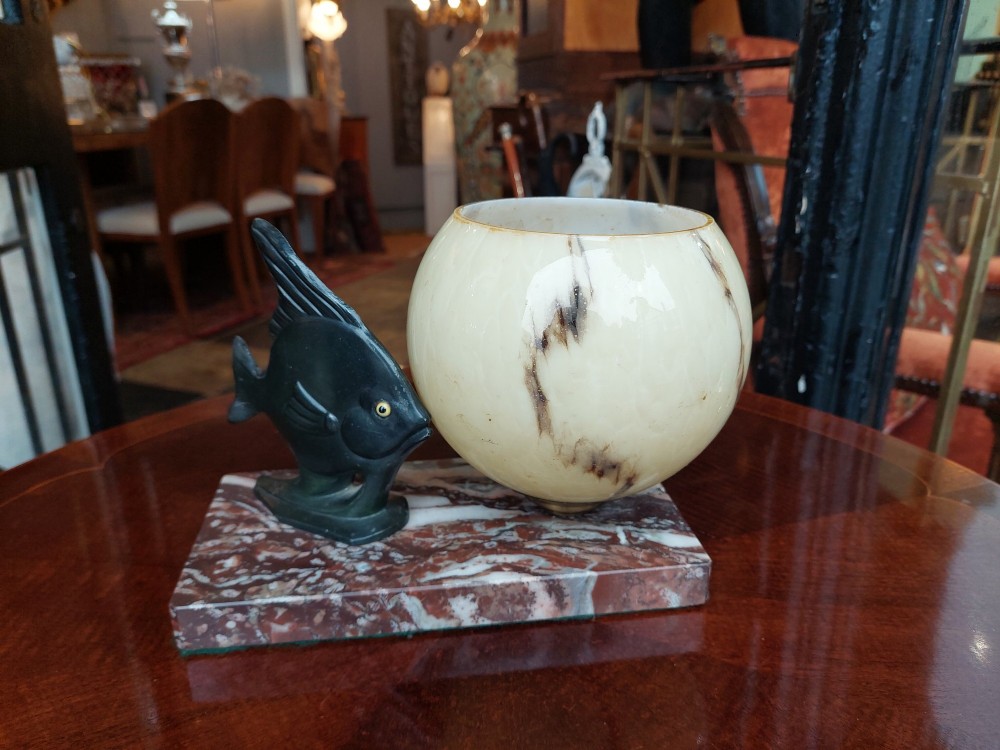 An Art Deco table lamp featuring a dark green patinated fish sculpture alongside a spherical cream glass shade, set on a rectangular variegated marble base. View IV