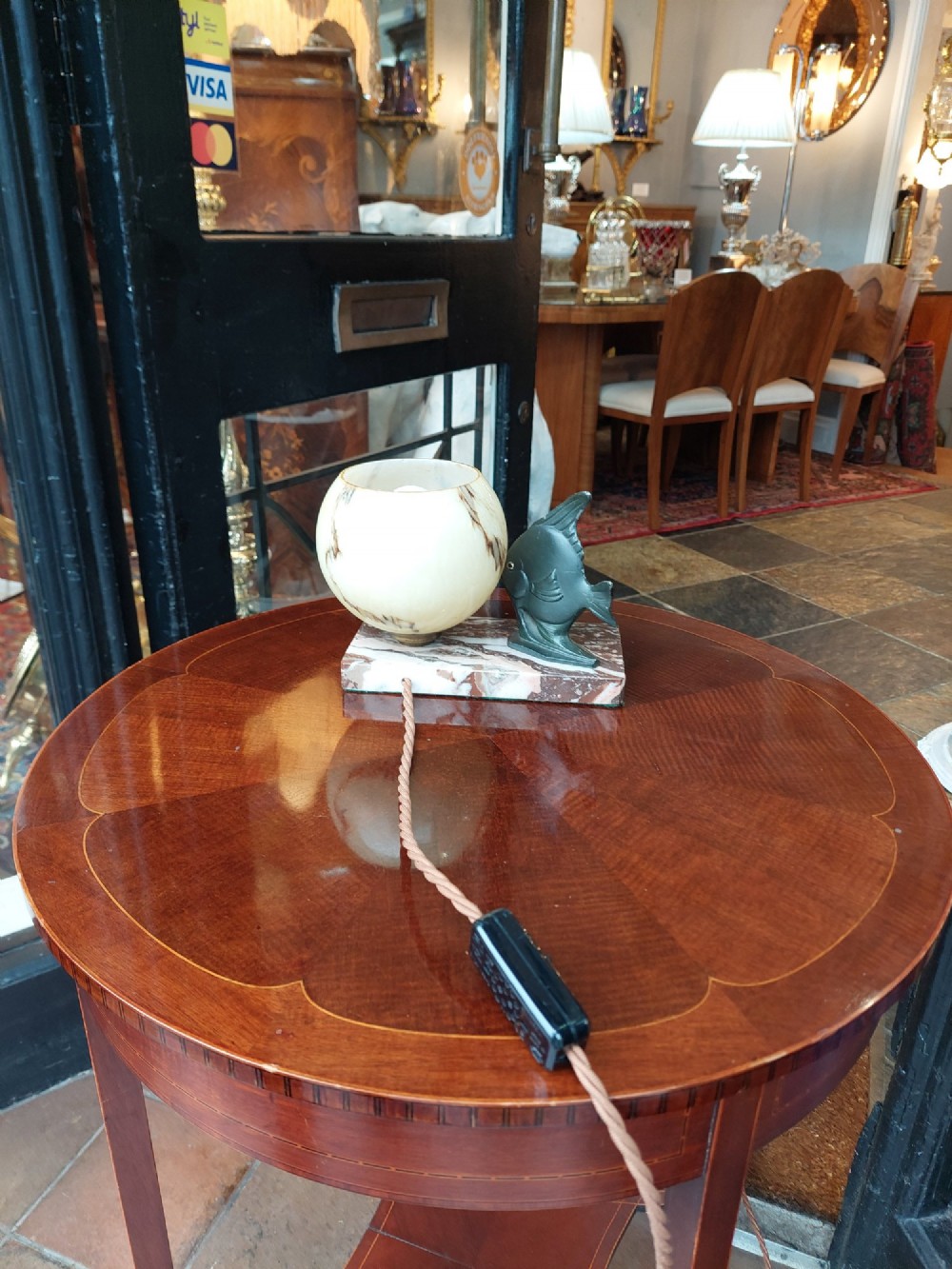 An Art Deco table lamp featuring a dark green patinated fish sculpture alongside a spherical cream glass shade, set on a rectangular variegated marble base. View VI