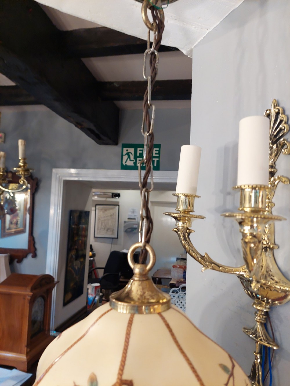 A 1920s cream glass pendant light shade hand painted with blue floral motifs, suspended from a brass chain. View IV