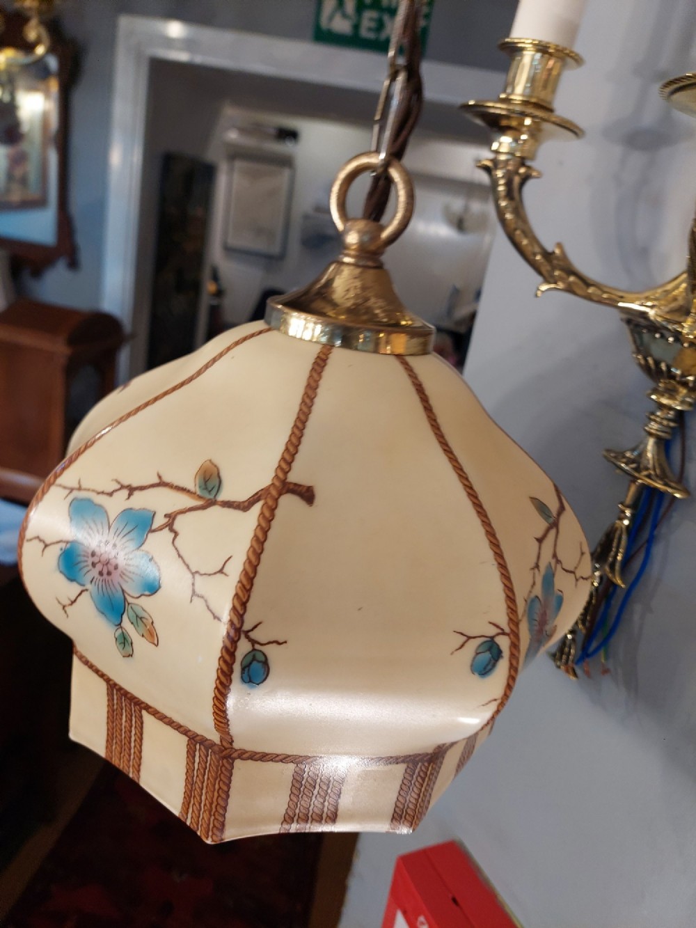 A 1920s cream glass pendant light shade hand painted with blue floral motifs, suspended from a brass chain. View V
