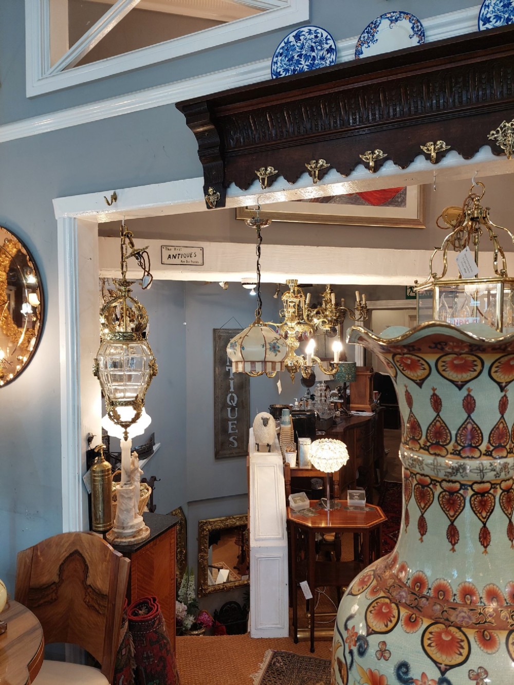 A 1920s cream glass pendant light shade hand painted with blue floral motifs, suspended from a brass chain. View VII