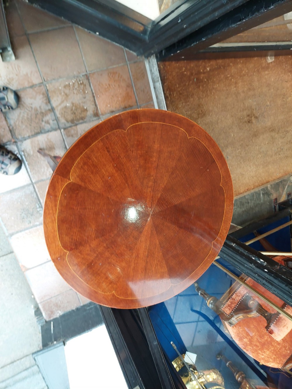 A circular Edwardian mahogany occasional table featuring a segmented veneer top with boxwood stringing inlay, splayed legs, and a lower concave stretcher shelf. View II