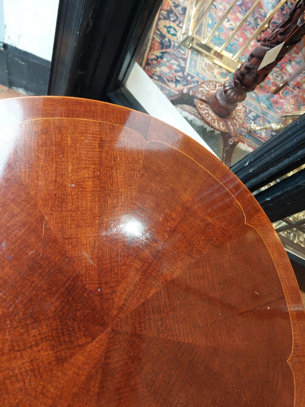 A circular Edwardian mahogany occasional table featuring a segmented veneer top with boxwood stringing inlay, splayed legs, and a lower concave stretcher shelf. View VI