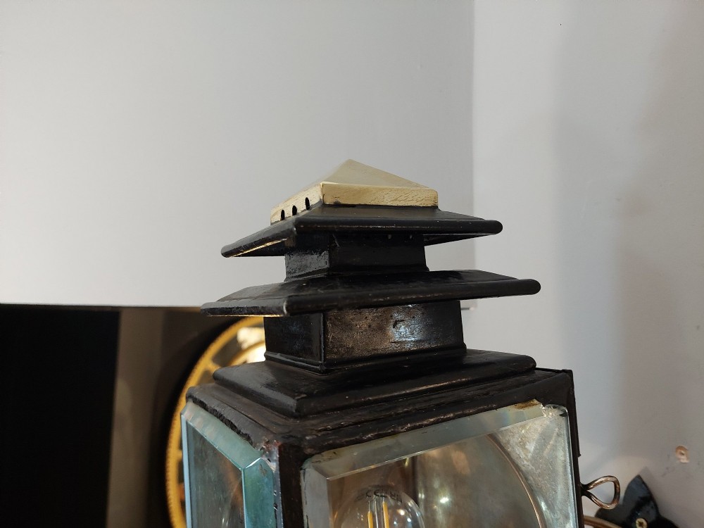 An antique black iron and polished brass carriage lamp mounted on a decorative scrolled wall bracket with bevelled glass panels. View IV