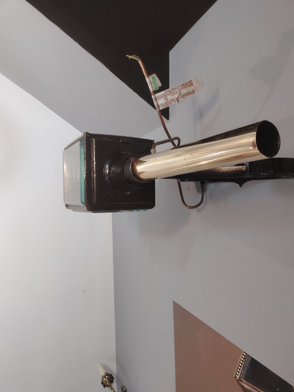 An antique black iron and polished brass carriage lamp mounted on a decorative scrolled wall bracket with bevelled glass panels. View IX