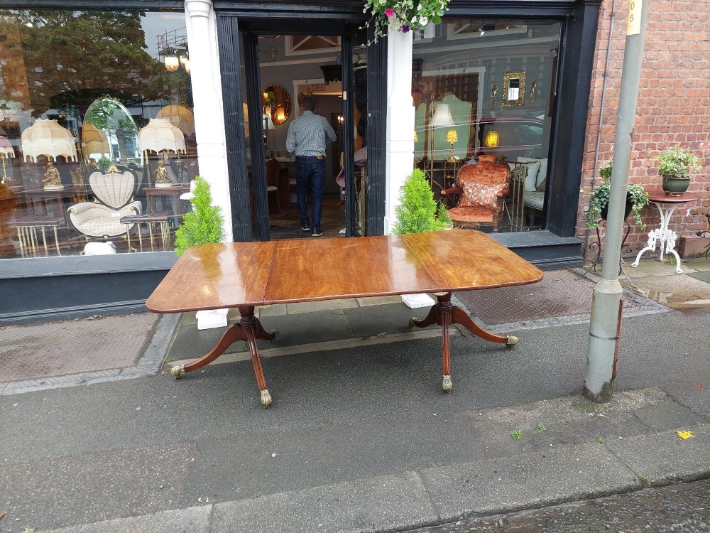 A Regency mahogany extendable dining table surrounded by matching dining chairs with striped upholstered seats. View X