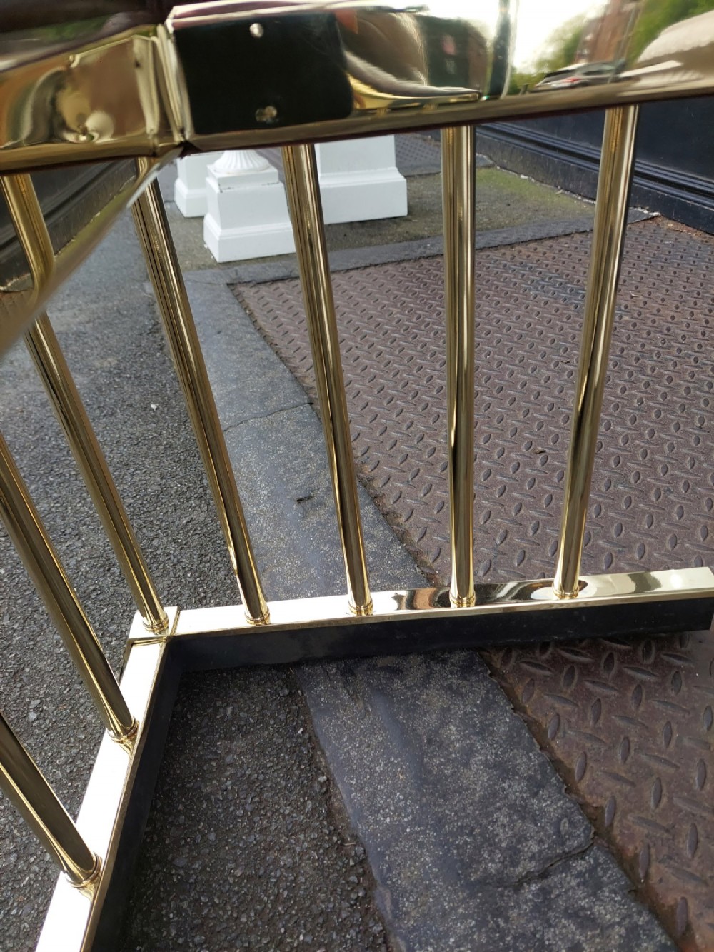 An early 20th-century brass club fender featuring a central dipped rail, vertical brass balusters, and two button-tufted dark red leather upholstered corner seats. View VIII