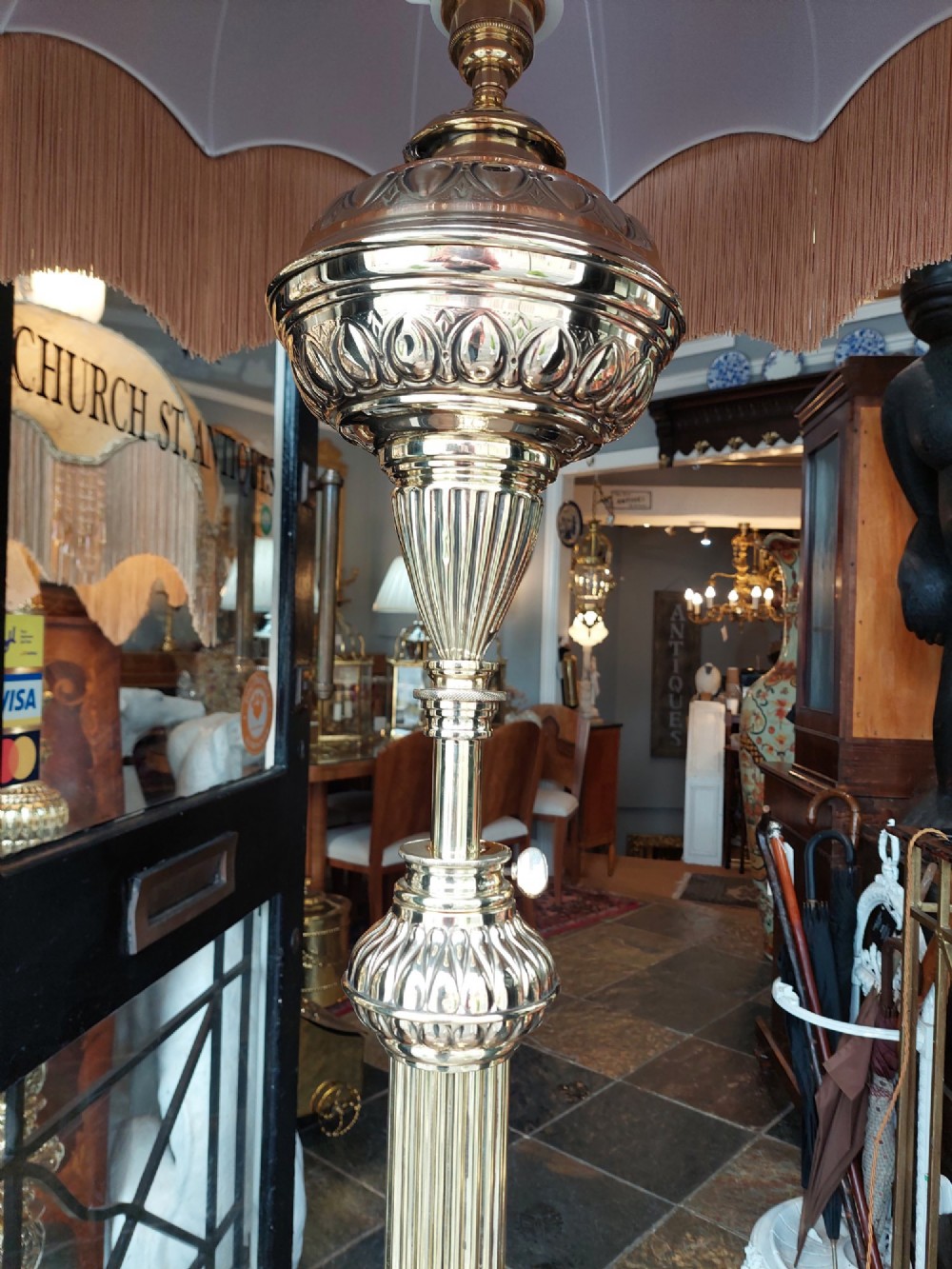 A Victorian brass extending standard floor lamp featuring a fluted column base and a deep red fabric shade with fringe detailing. View VI
