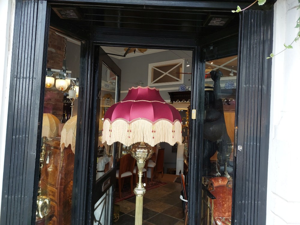 A Victorian brass extending standard floor lamp featuring a fluted column base and a deep red fabric shade with fringe detailing. View VIII