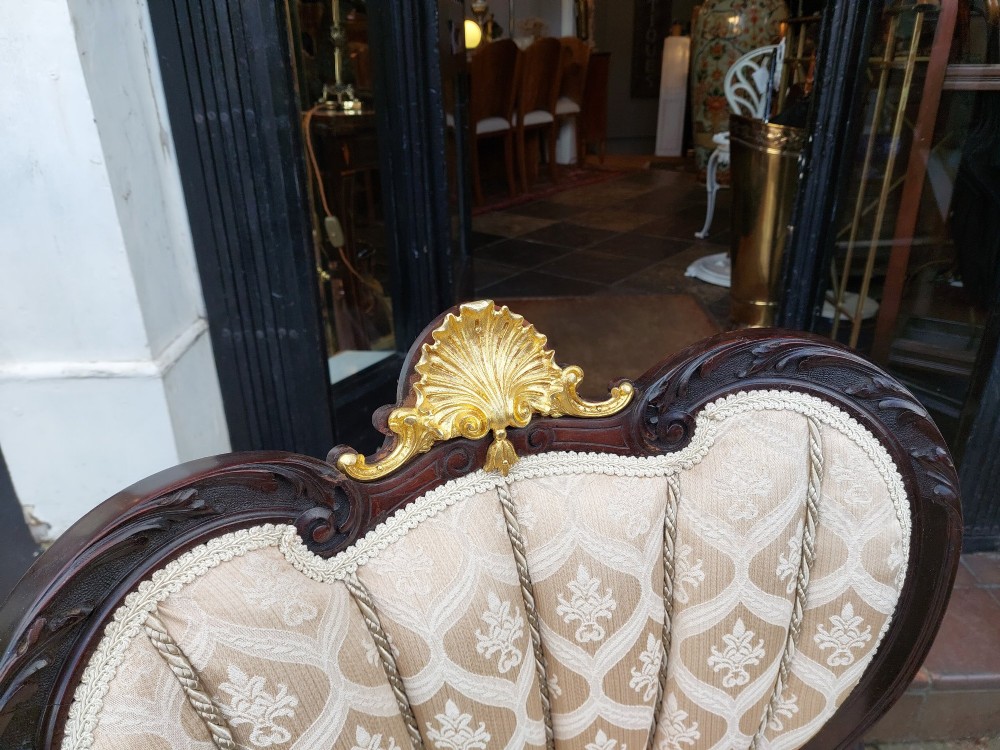 An upholstered French Empire style mahogany armchair featuring gilt bronze mounts, a channelled backrest, cream fabric, and brass castors. View II