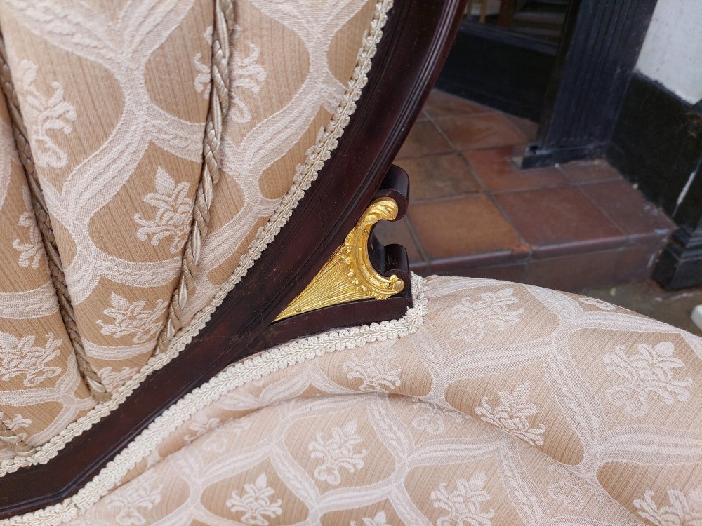 An upholstered French Empire style mahogany armchair featuring gilt bronze mounts, a channelled backrest, cream fabric, and brass castors. View III