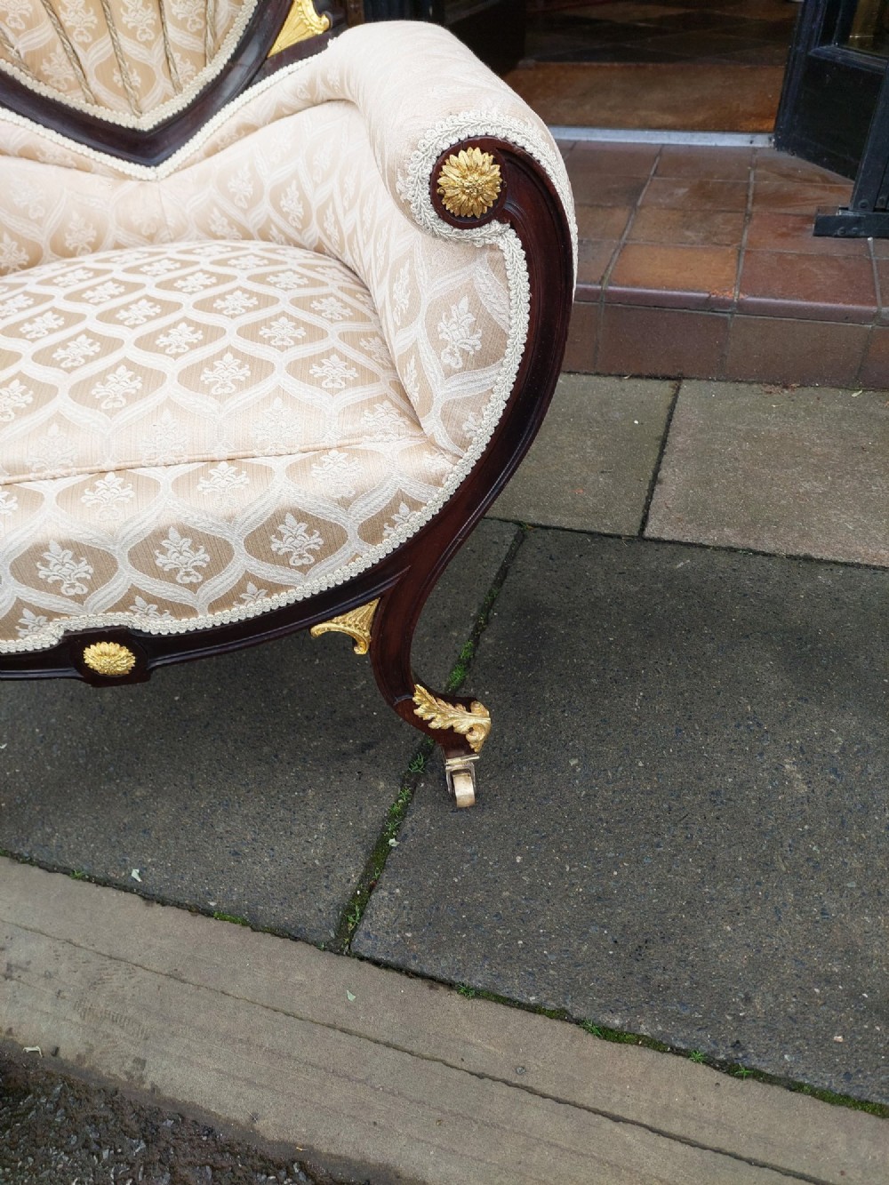 An upholstered French Empire style mahogany armchair featuring gilt bronze mounts, a channelled backrest, cream fabric, and brass castors. View IV