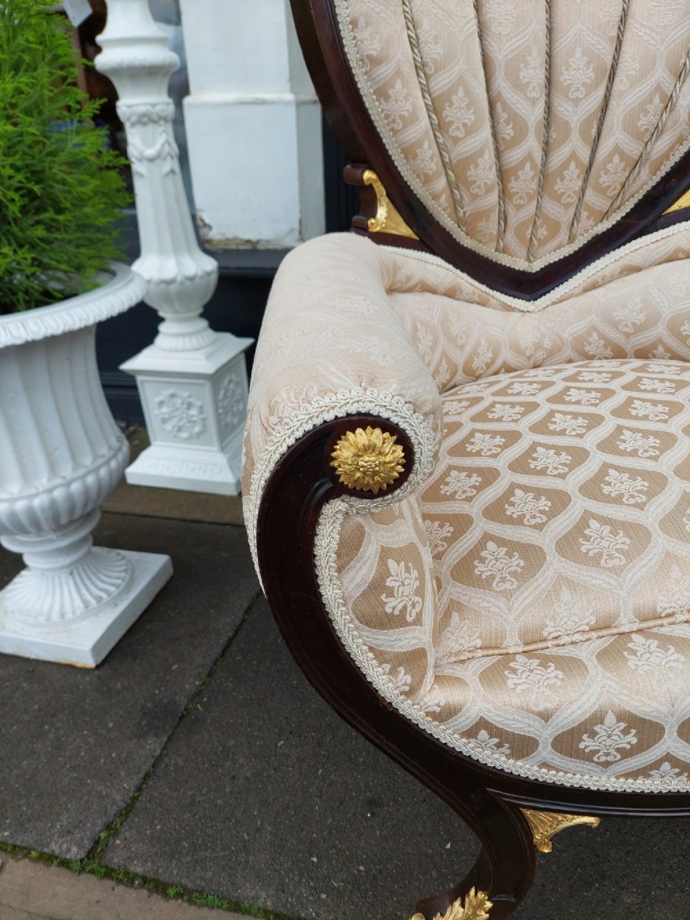 An upholstered French Empire style mahogany armchair featuring gilt bronze mounts, a channelled backrest, cream fabric, and brass castors. View VII