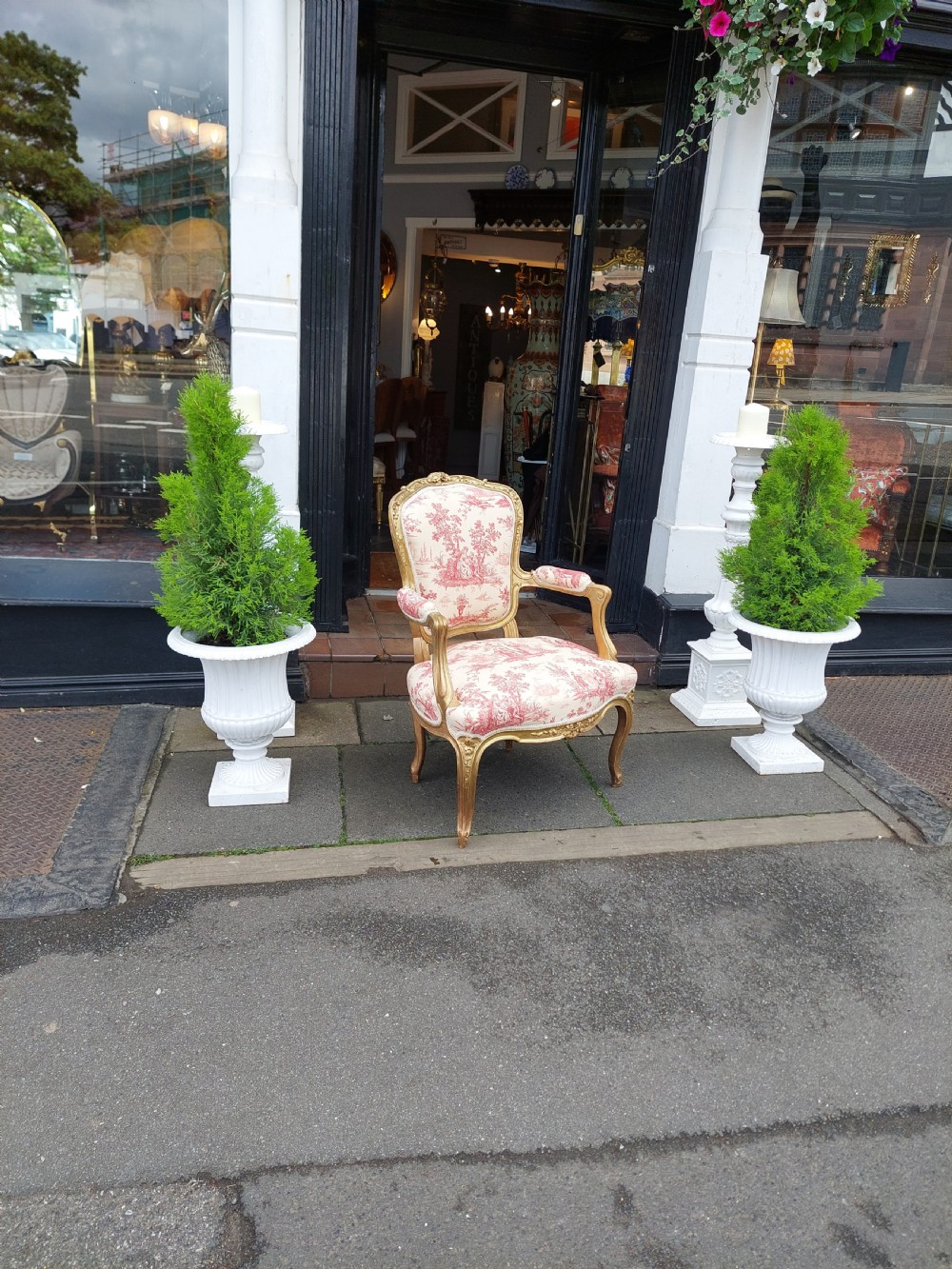 A late 19th-century French Rococo Revival giltwood open armchair upholstered in red and white Toile de Jouy patterned fabric featuring cabriole legs and floral carvings. View II