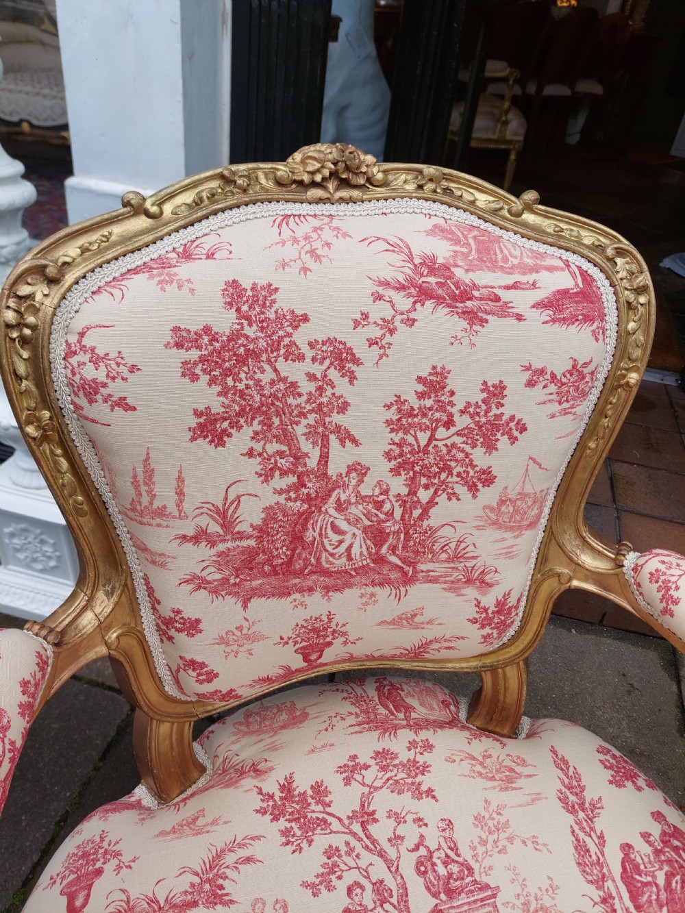 A late 19th-century French Rococo Revival giltwood open armchair upholstered in red and white Toile de Jouy patterned fabric featuring cabriole legs and floral carvings. View IV
