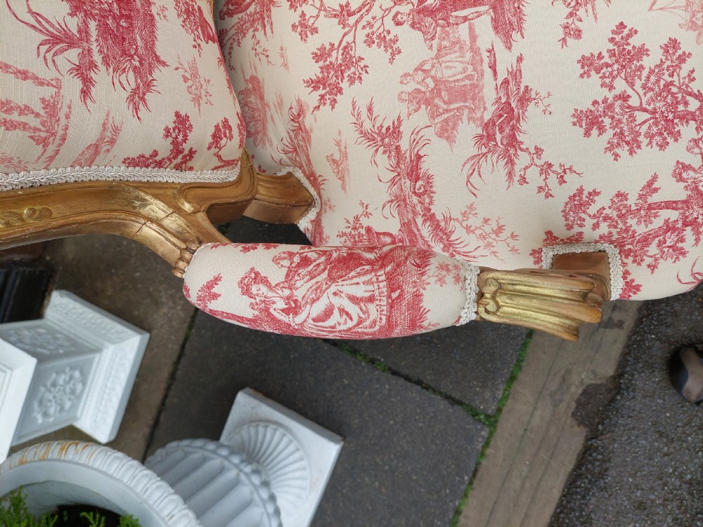 A late 19th-century French Rococo Revival giltwood open armchair upholstered in red and white Toile de Jouy patterned fabric featuring cabriole legs and floral carvings. View VII