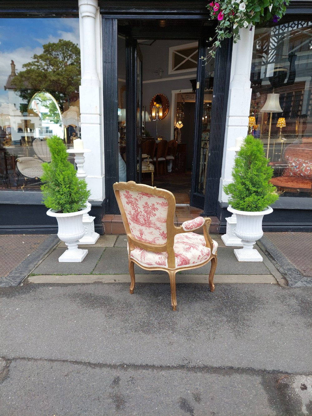 A late 19th-century French Rococo Revival giltwood open armchair upholstered in red and white Toile de Jouy patterned fabric featuring cabriole legs and floral carvings. View VIII