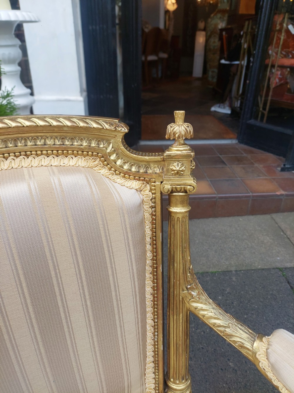 A mid-Victorian giltwood fauteuil armchair with carved golden wood framing, fluted legs, and cream striped upholstery. View IV